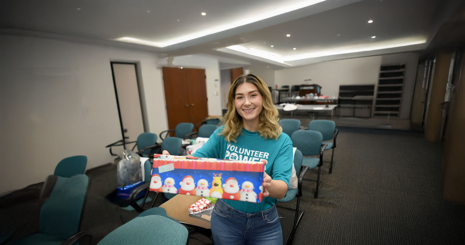 Female Idaho Power employee smiling and holding up a wrapped present