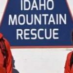 Permalink to Idaho Power Donates Safety Gear to Idaho Mountain Search and Rescue Four people in red jackets standing in front of a blue sign shaped like a mountain with the words Idaho Mountain Rescue on it.
