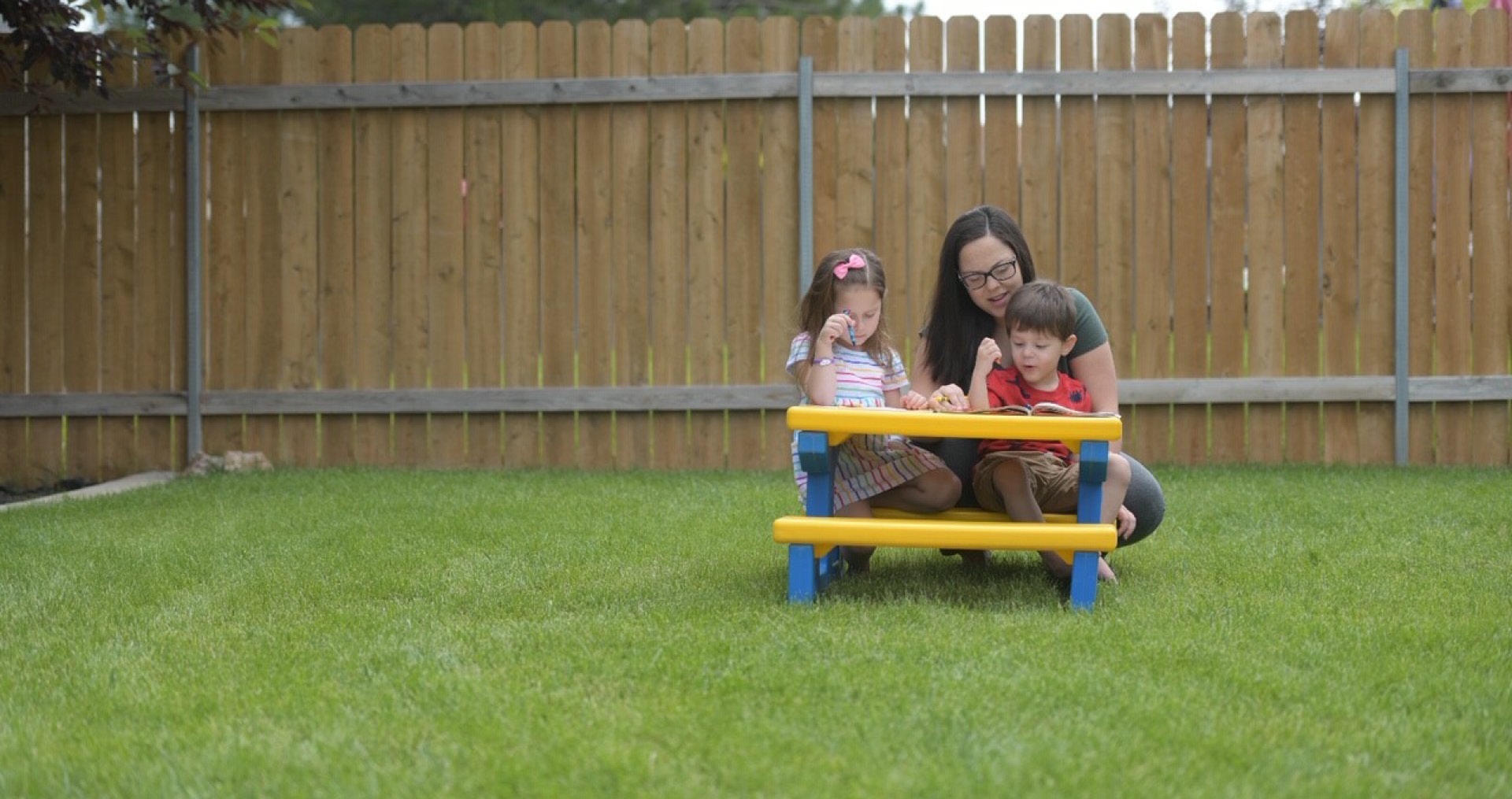 Image of a family coloring at a picnic table