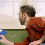 Man in house caulking window