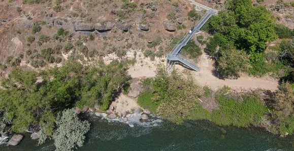 Aerial view of metal stairs descending from the canyon rim to the riverbank.