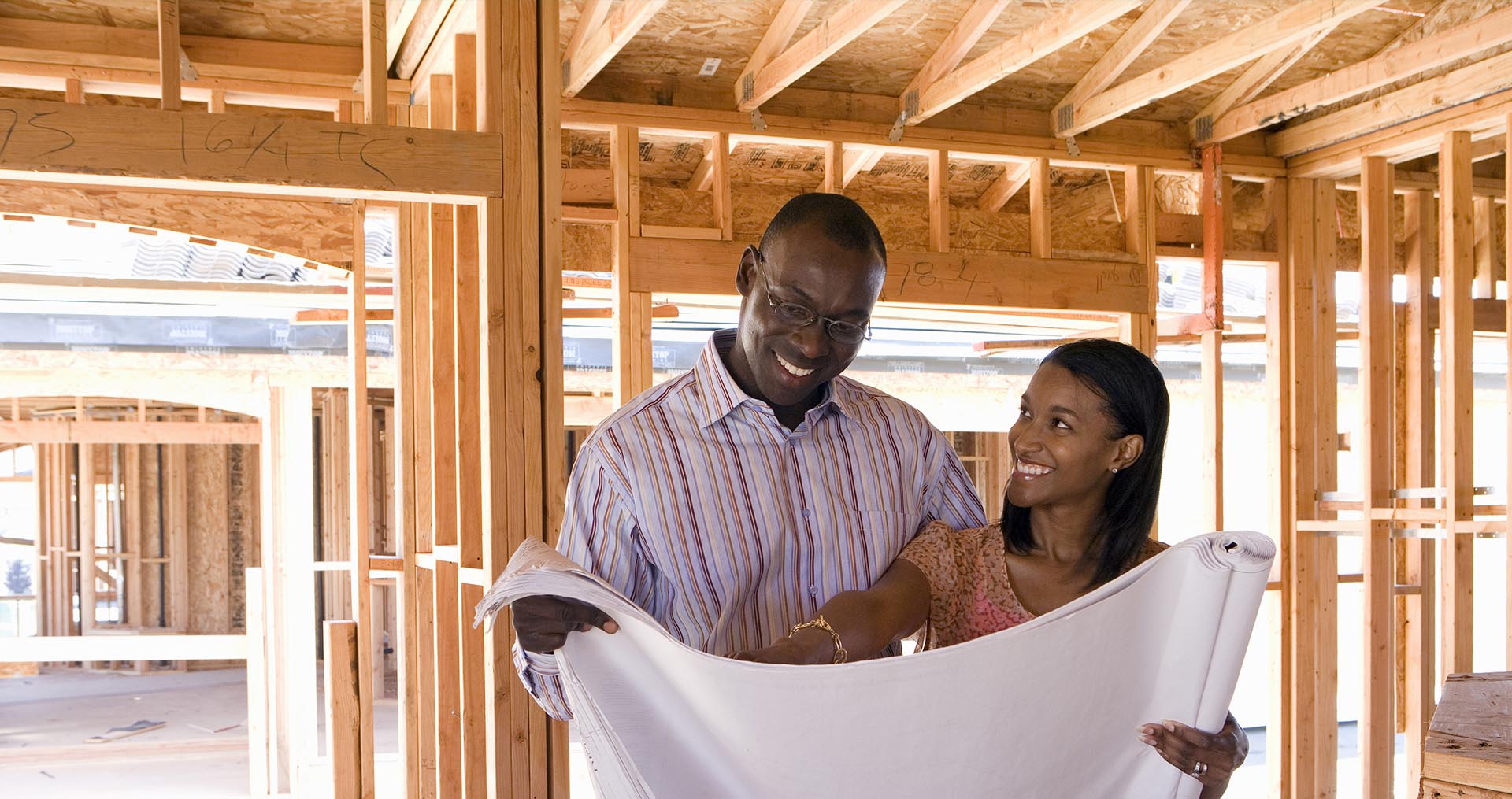 a couple standing in a newly framed house