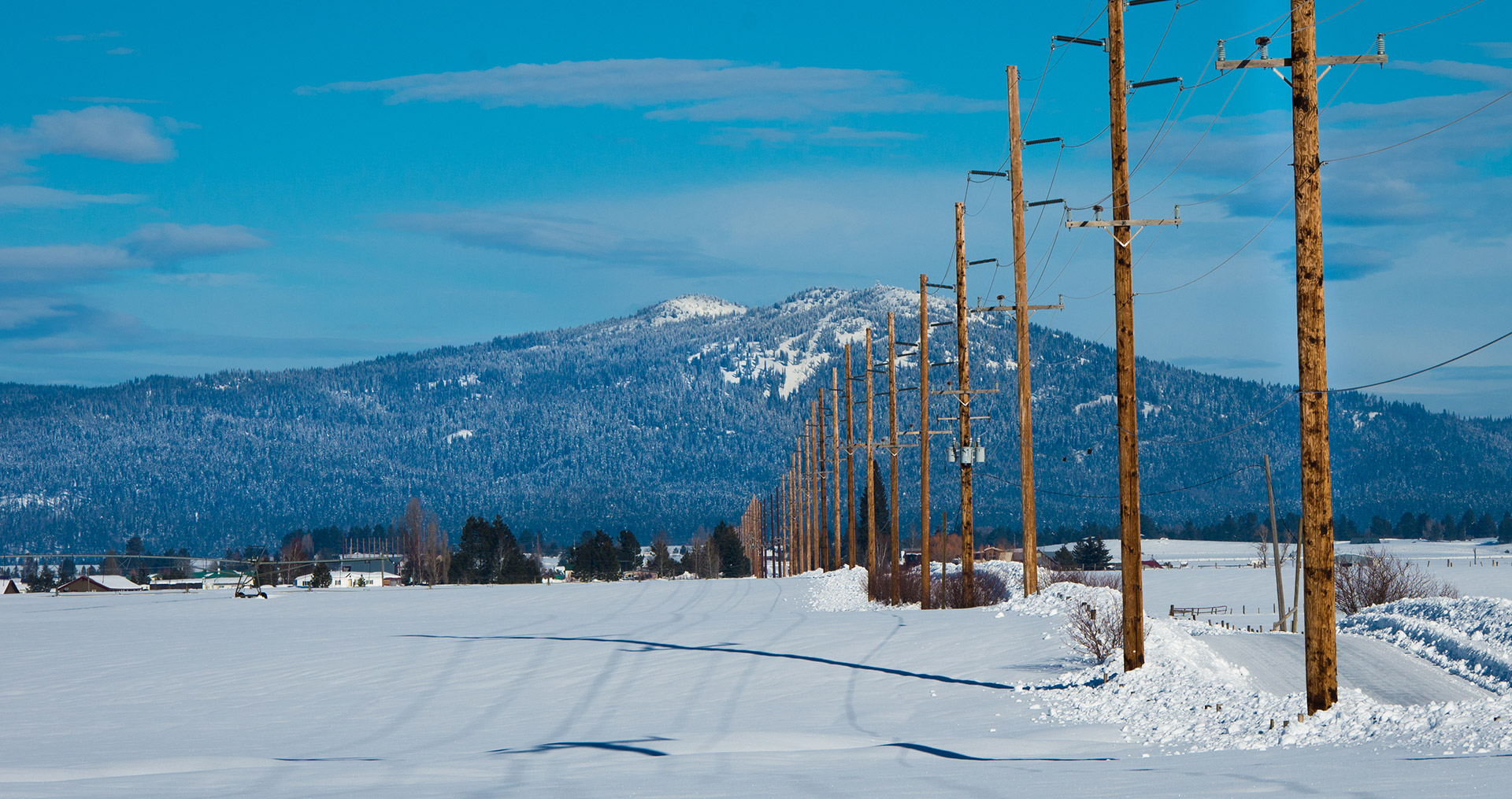 Winter scene of snow, power lines, and mountains.